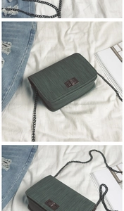 Detail of dark green chain crossbody bag with horizontal texture and metal twist lock