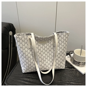 Detail of white tote bag with gray M-pattern texture and gold FASHION metal plate