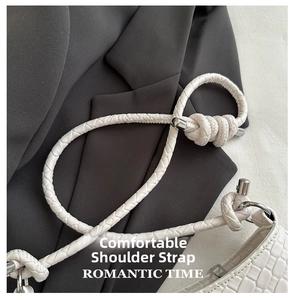 Detail of white woven shoulder strap with metallic buckle on a gray blazer background
