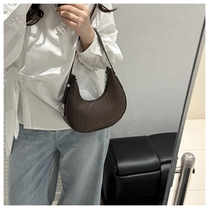 Detailed close-up of dark brown crescent bag with woven texture and silver metal buckle
