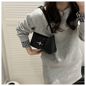 Detail of black underarm bag with embossed leather texture and silver star buckle