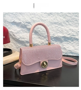 Détail du sac à main rose pailleté avec fermoir doré sur une table en bois foncée