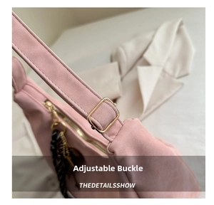 Detail of pink faux suede bag featuring adjustable metal buckle and decorative scarf