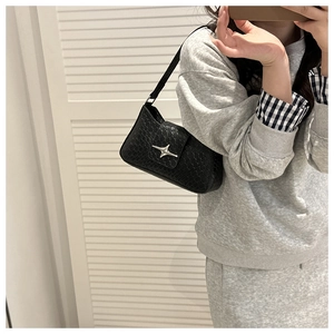 Close-up of black hobo shoulder bag with crocodile texture and silver star buckle detail