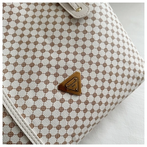Gros plan du sac fourre-tout minimaliste avec logo en bronze vintage et motif floral