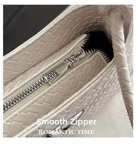 Detailed macro view of smooth silver metal zipper on cream woven leather crossbody bag
