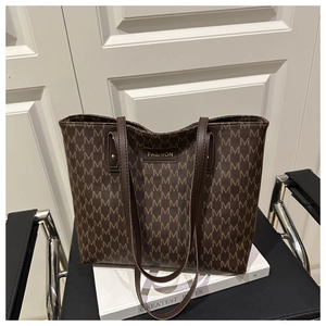 Detailed macro of dark brown tote bag featuring luxury letter pattern and gold hardware