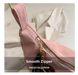 Detail of smooth gold zipper and texture on pink suede tote bag with stylish charms