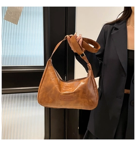 Detail of vintage brown leather hobo bag with embossed lettering and adjustable strap