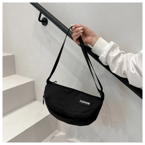 Detail of minimalist black crossbody crescent bag with adjustable strap and fashion label
