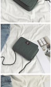 Detail of dark green ribbed crossbody bag with metallic rotary lock and chain strap