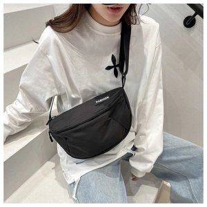 Close-up of black crescent moon bag on model featuring white FASHION woven label detail