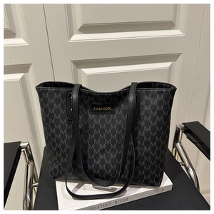 Detail of monogram patterned tote bag with fashion label on a minimalist chair