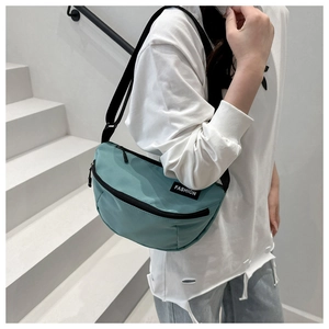 Detail of mint green nylon crossbody bag showing the fashion label and adjustable strap