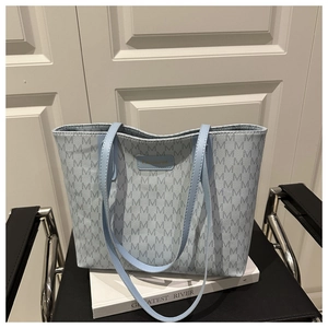 Detail of light blue tote bag with grey M-pattern and faux leather shoulder straps