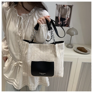 Detail of woven straw tote bag with black leather pocket and silver chain handle