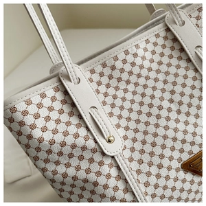 Détails de la texture en cuir à fleurs rétro et logo doré sur un sac cabas beige