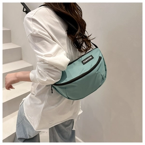 Detail of light green canvas crossbody bag with Fashion label and zip pockets