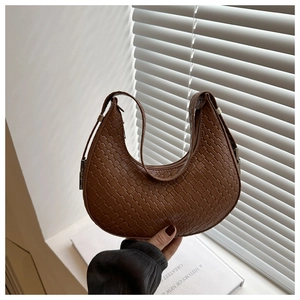 Detail of brown woven crescent bag showing hand-knitted leather texture and zipper closure