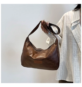 Detail of a brown vintage hobo bag with 'FASHION' label and textured leather strap
