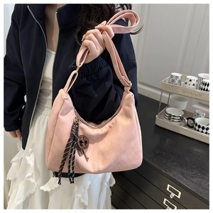 Pink faux leather hobo bag with pretzel charm and ribbon shown on shoulder