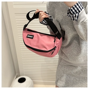 Close-up of pink crescent saddle bag featuring durable nylon fabric and fashion woven label