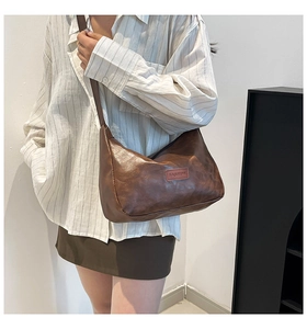 Detail view of brown vintage shoulder bag with textured leather and fashion label