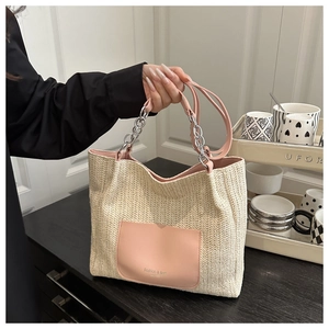Close-up of woven straw tote bag with pink leather pocket and silver chain handle detail
