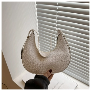 Detail of white crescent bag with woven texture on a minimalist home background