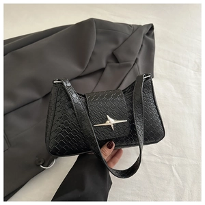 Close-up of black woven underarm bag with silver star buckle and faux leather texture