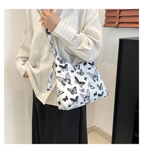 Foto lifestyle della borsa tote in tela bianca con motivi a farfalla neri e tracolla larga