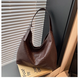 Close-up of dark brown woven leather hobo bag with detailed craftsmanship and fashion tag