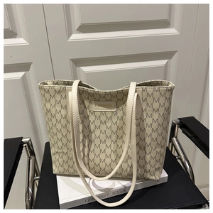 Close-up of beige tote bag with M-pattern texture and fashion leather label on a chair