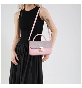 Side view of elegant pink leather handbag with gold metal lock on a female model