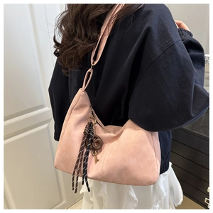 Detail of pink matte hobo bag featuring knotted tassel decoration on a female model