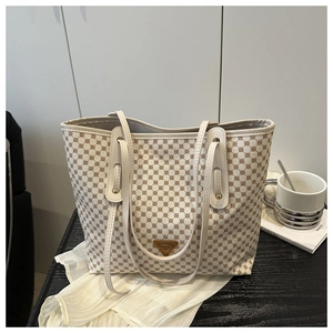 Détail du sac cabas à motif géométrique avec logo en métal sur du bois