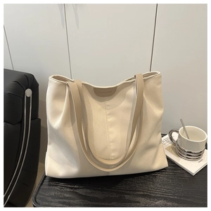 Détail du cabas en toile beige avec anses en cuir marron sur table en bois noir