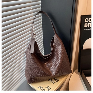 Macro view of woven dark brown leather texture and fashion tag on the hobo tote bag
