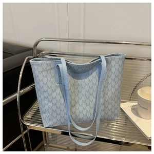 Close-up of light blue monogram tote bag with fashion tag on a metal display stand