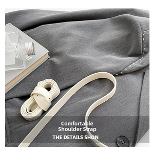 Détail du sac en sergé gris avec bandoulière en cuir crème et fermeture à bouton noir