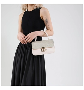 Detail of silver sequin flap and gold hollow twist lock on white leather handbag