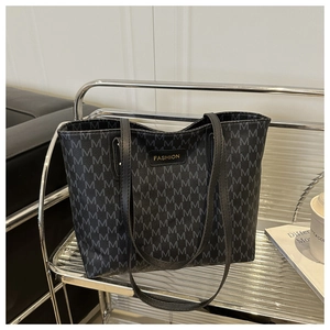 Detail of large tote bag featuring monogram pattern on a modern metal display shelf