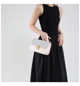 Close-up of sparkling silver sequins and golden interlocking clasp on the pink handbag