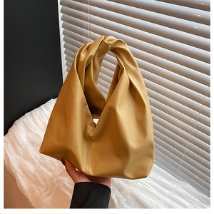 Detail of mustard yellow hobo bag with unique knotted handle and soft leather texture