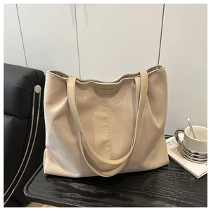 Gros plan du sac cabas beige avec poignées en cuir et logo brodé de haute qualité