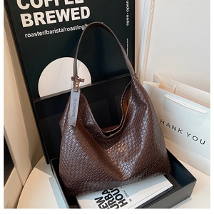 Detail of dark brown woven leather hobo bag texture with a decorative fashion tag