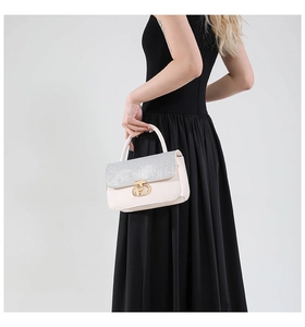 Close-up of light pink handbag featuring silver sequin flap and gold clasp hardware