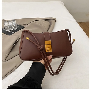 Detail of dark brown leather shoulder bag with gold clasp and knotted strap detail