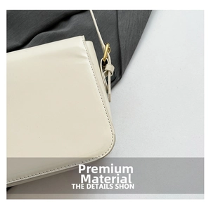 Détail de la texture cuir crème lisse et des boucles en métal doré du sac à bandoulière