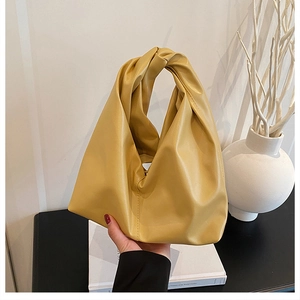 Close-up of mustard yellow bucket bag with knot handle and pleated texture design
